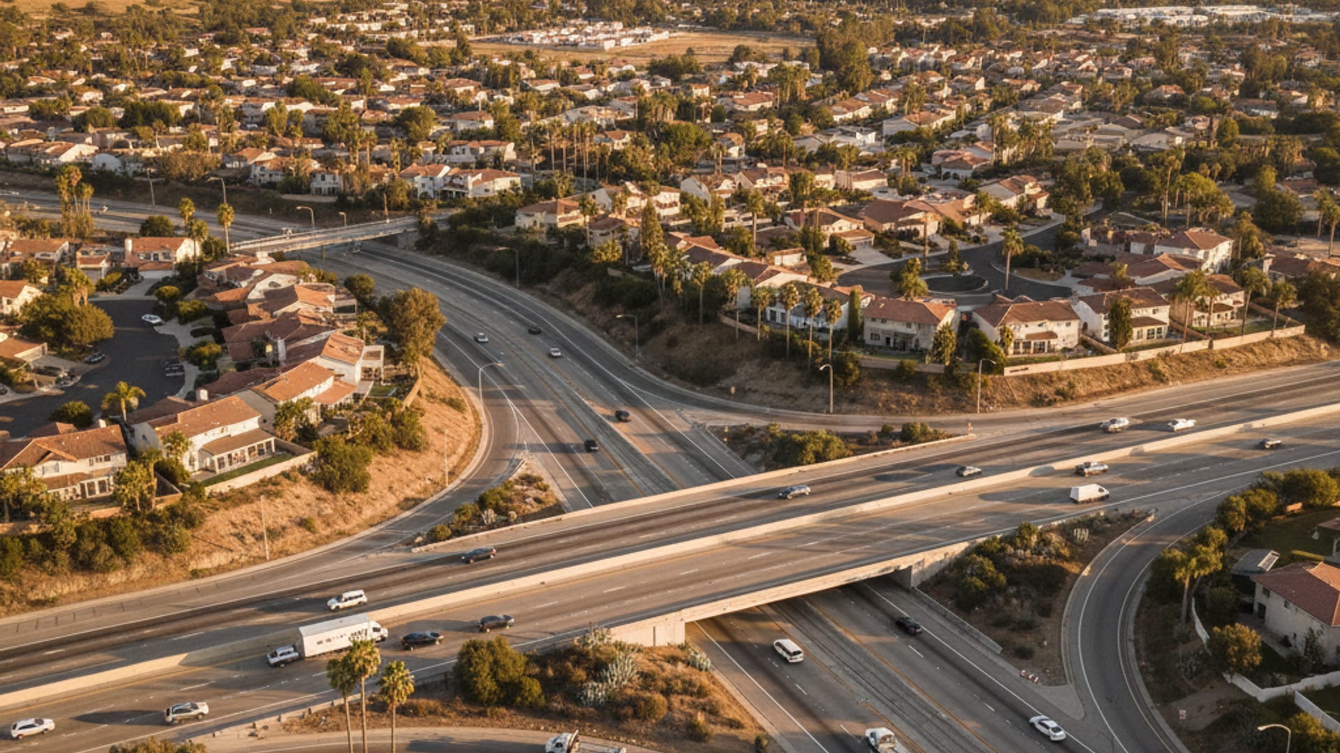 Elevated drone view of a Coastal Bend highway network with residential neighborhoods and the bay at golden hour